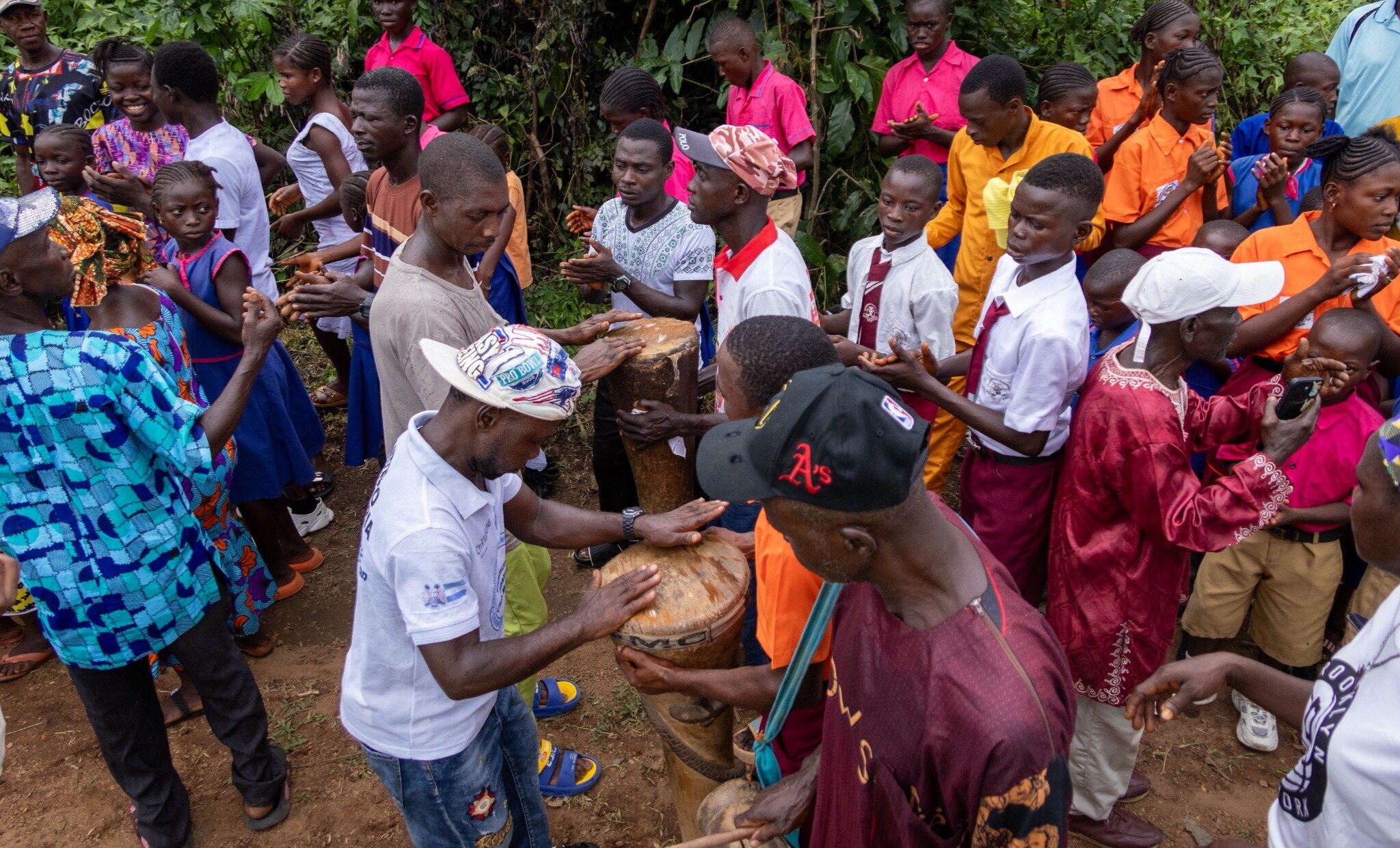 Community members playing drums and celebrating together near a completed well in Sierra Leone
