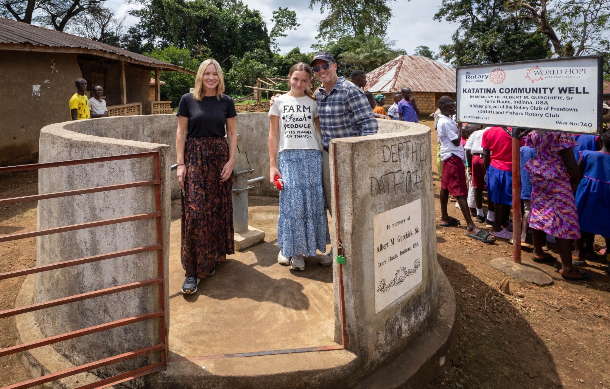 Three WaterIsLife visitors standing beside a completed community well in Sierra Leone