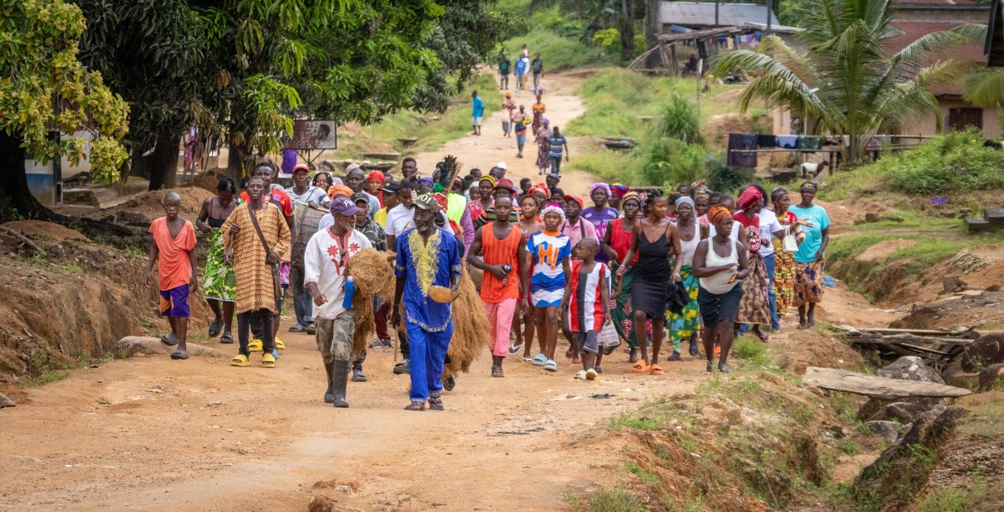 Community members walking together in a village procession in Sierra Leone